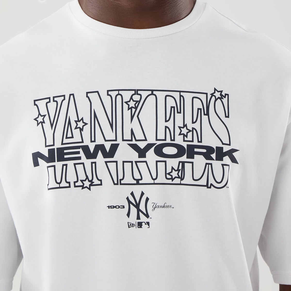 New Era New York Yankees MLB Graphic White Oversized T-Shirt, front view showing the printed Yankees logo with stars across the chest, New York lettering underneath, and the NY emblem with 1903 and Yankees script at the bottom centre.