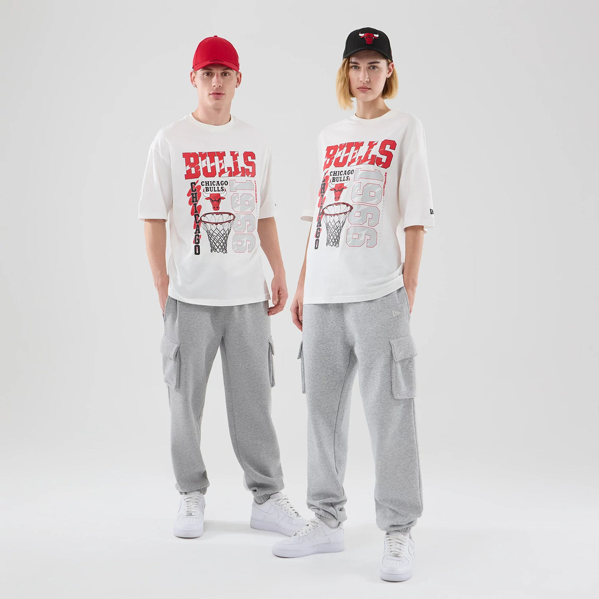 New Era Chicago Bulls NBA Script Graphic White Oversized T-Shirt, front view on-model showing the red Bulls lettering across the chest with a black and red basketball net graphic underneath and the numbers 1966 in grey on the lower right.