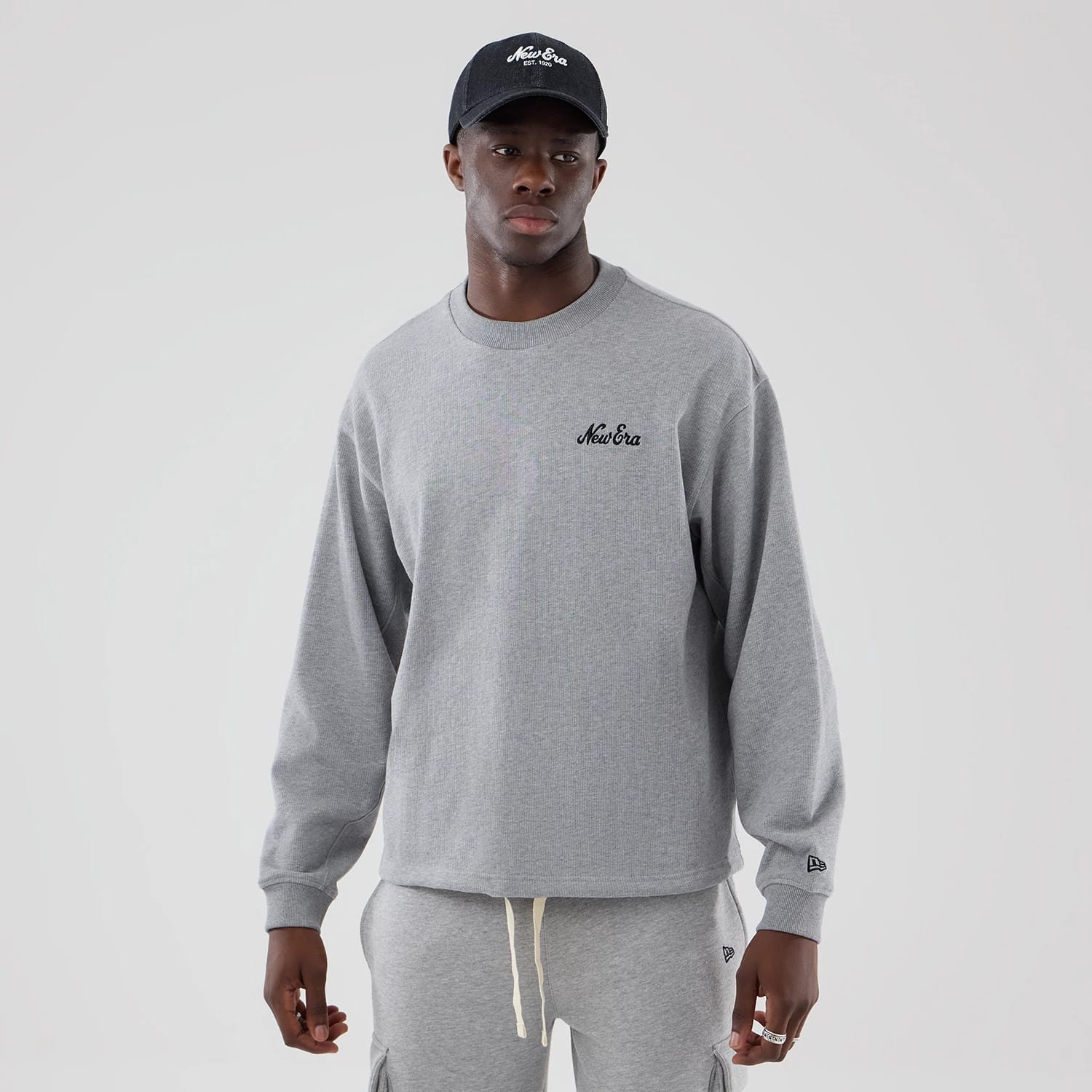 The model is wearing this New Era Oversized Crew Neck Sweater in grey. 1