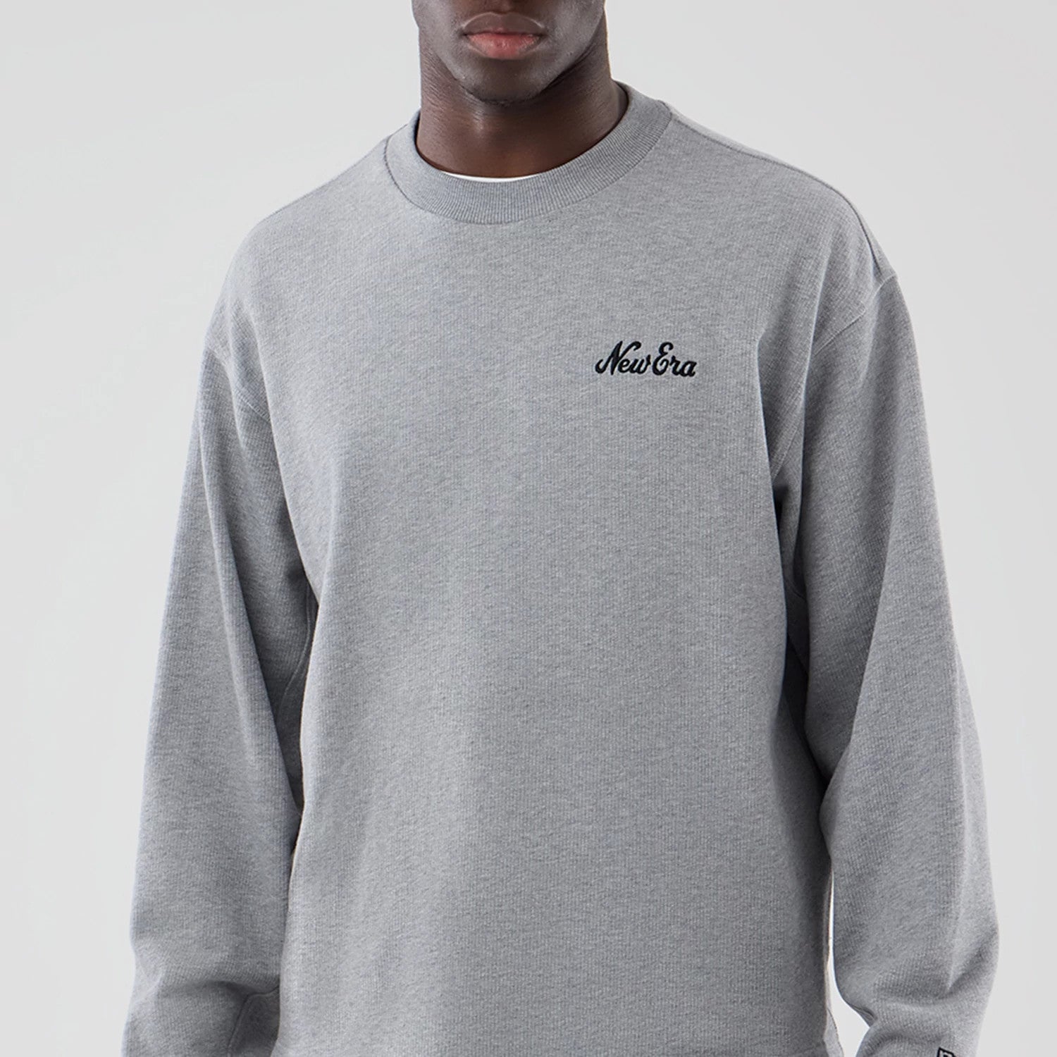 The model is wearing this New Era Oversized Crew Neck Sweater in grey. 3