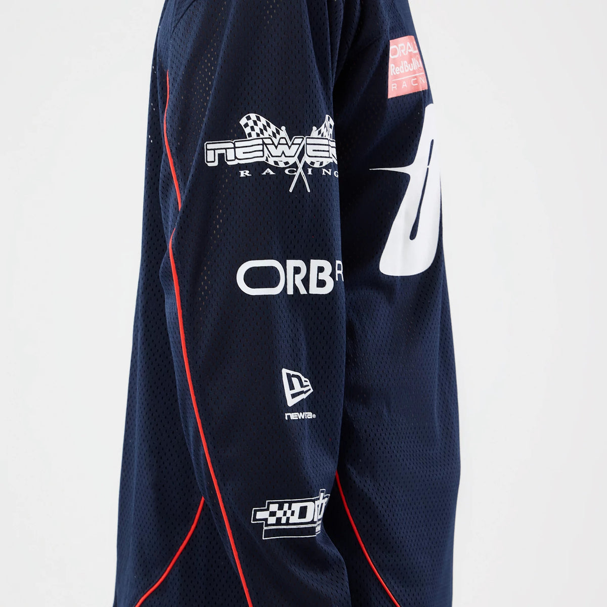 New Era Red Bull Racing Dark Blue Hockey Jersey, side view showing the mesh fabric with white 'New Era Racing' and 'ORB' lettering on the sleeves, accented by red piping along the arm and a New Era flag logo near the cuff.