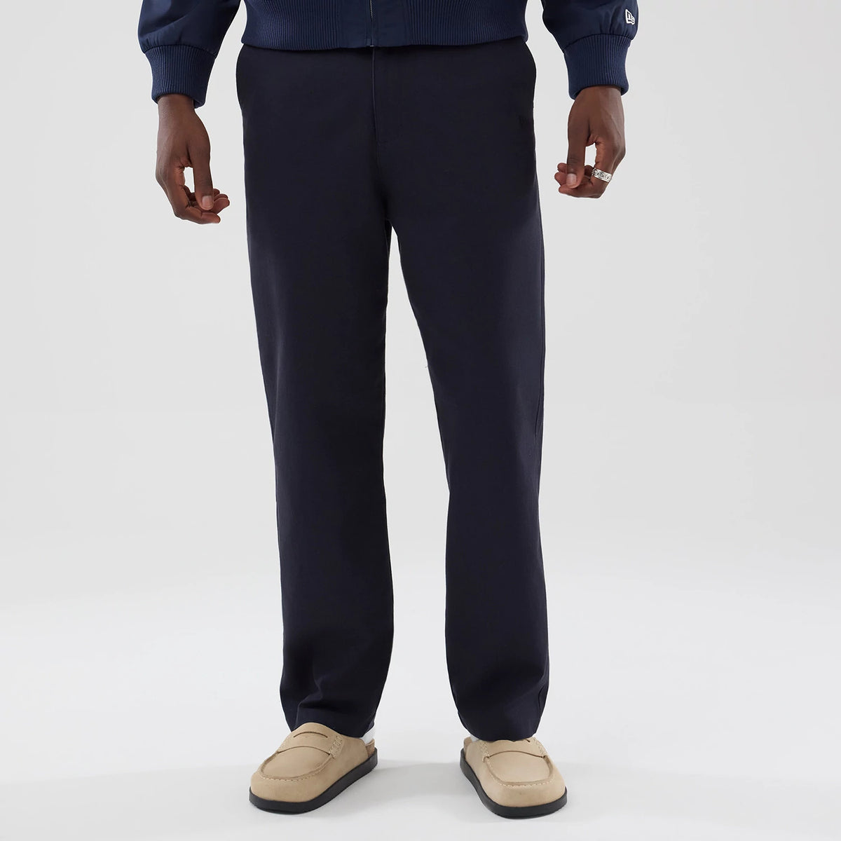 New Era Navy Chino Trousers, front view on a model styled with a navy sweater, showing a clean, flat-front design with a straight leg fit, paired with casual beige loafers for a sophisticated, relaxed look.