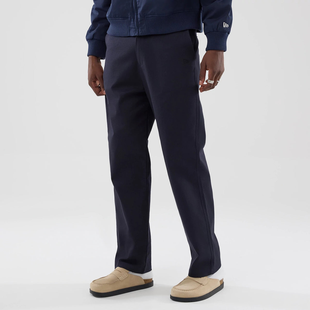 The model is wearing these New Era Chino Trousers in navy. 3