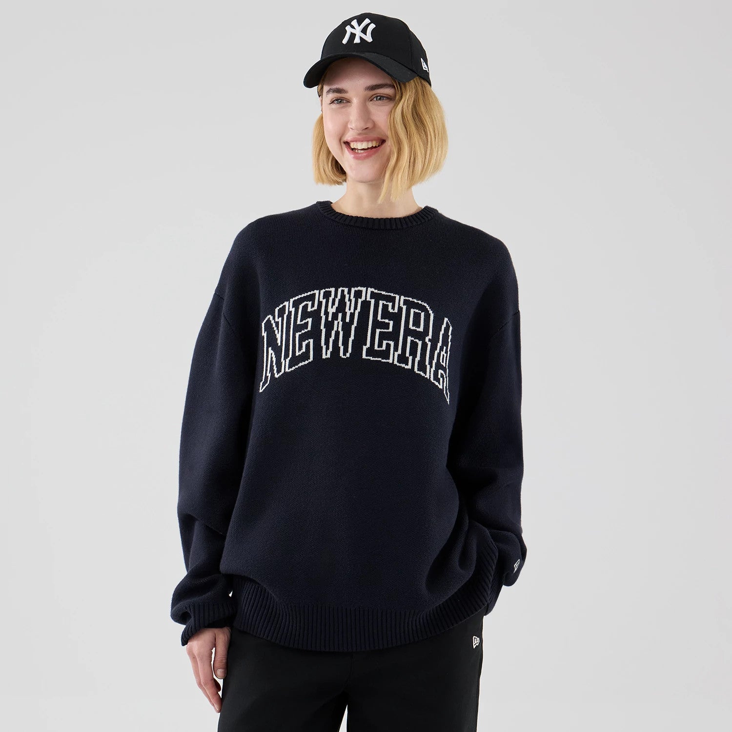 The model is wearing this New Era Knit Script Knitted Sweater in navy. 4