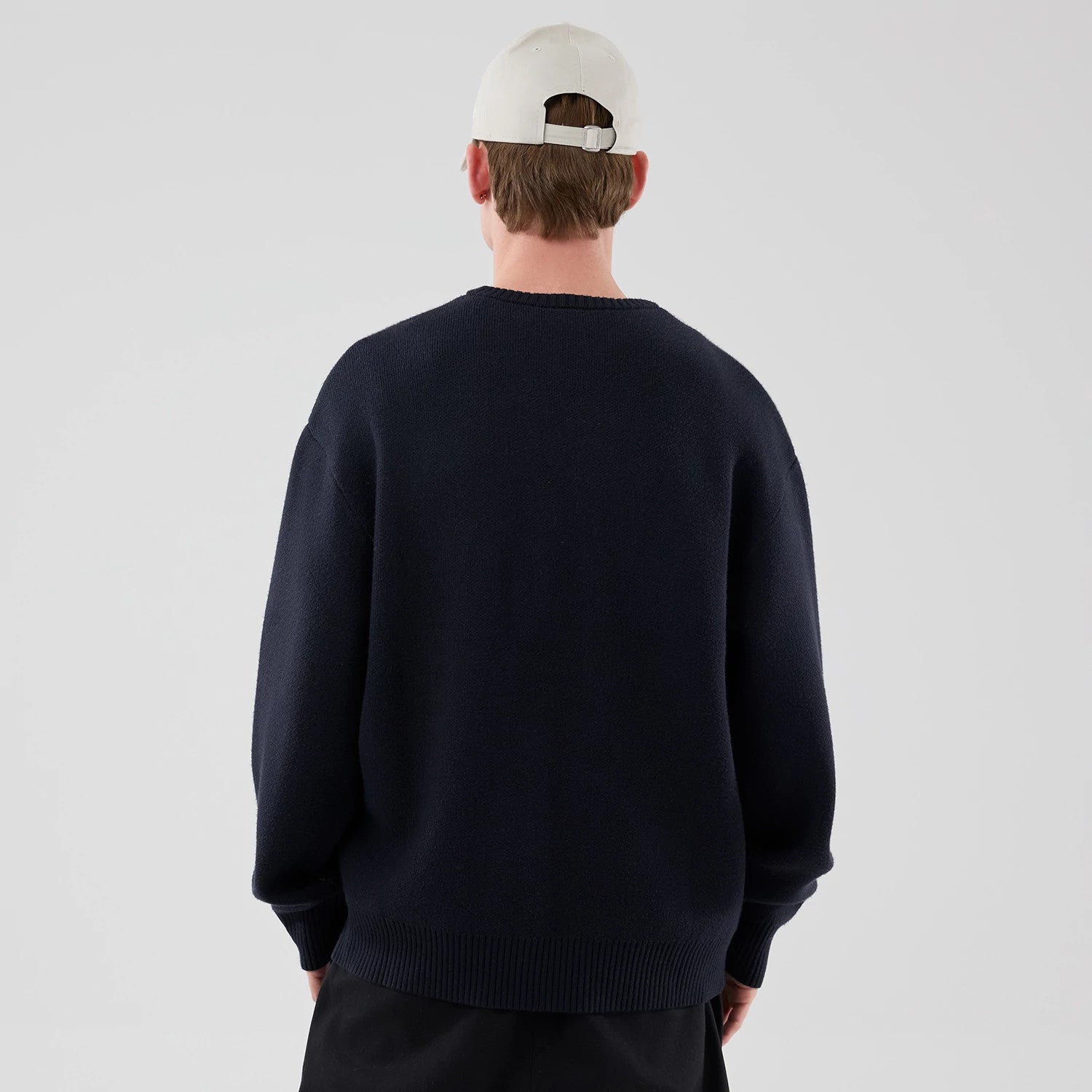 The model is wearing this New Era Knit Script Knitted Sweater in navy. 2