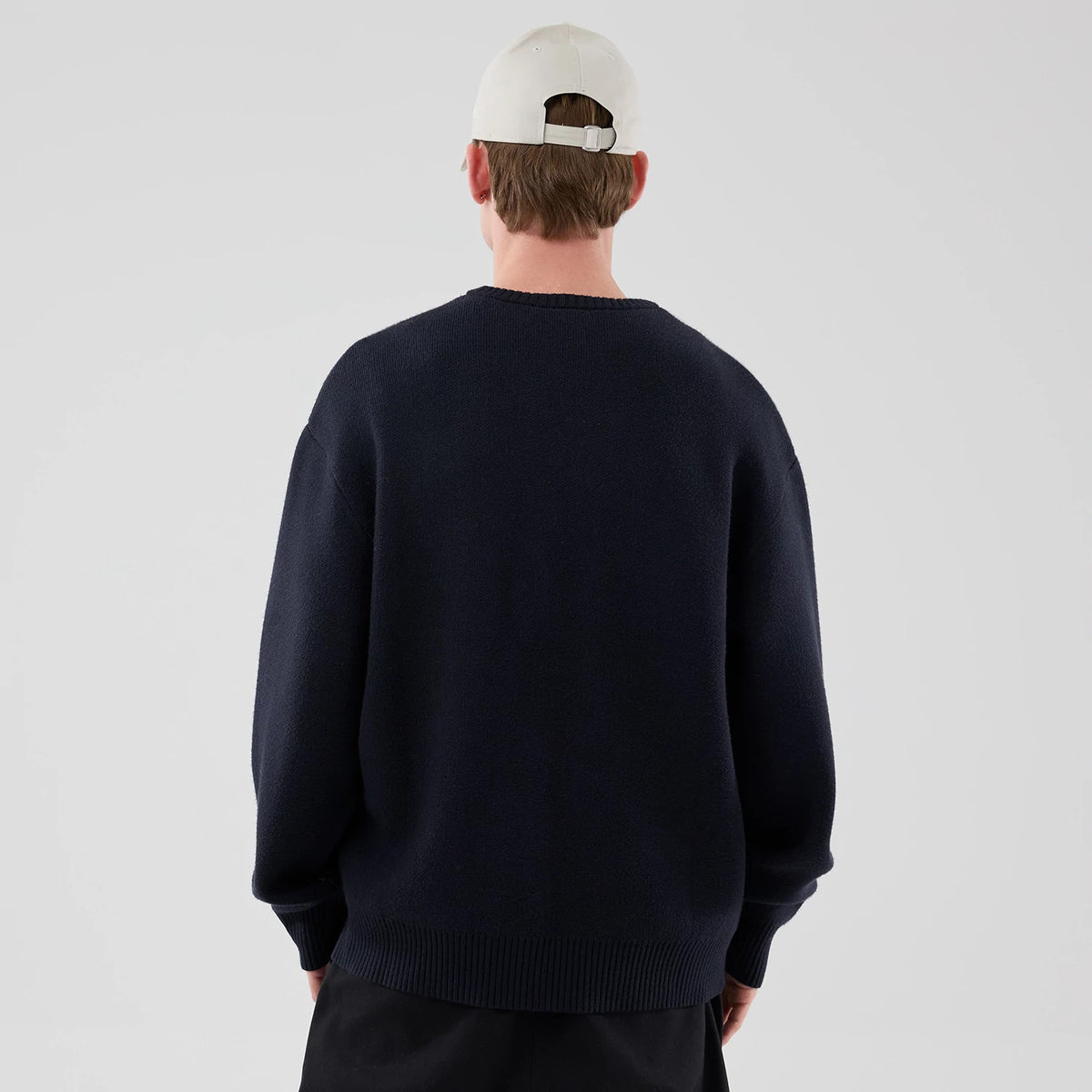 The model is wearing this New Era Knit Script Knitted Sweater in navy. 2