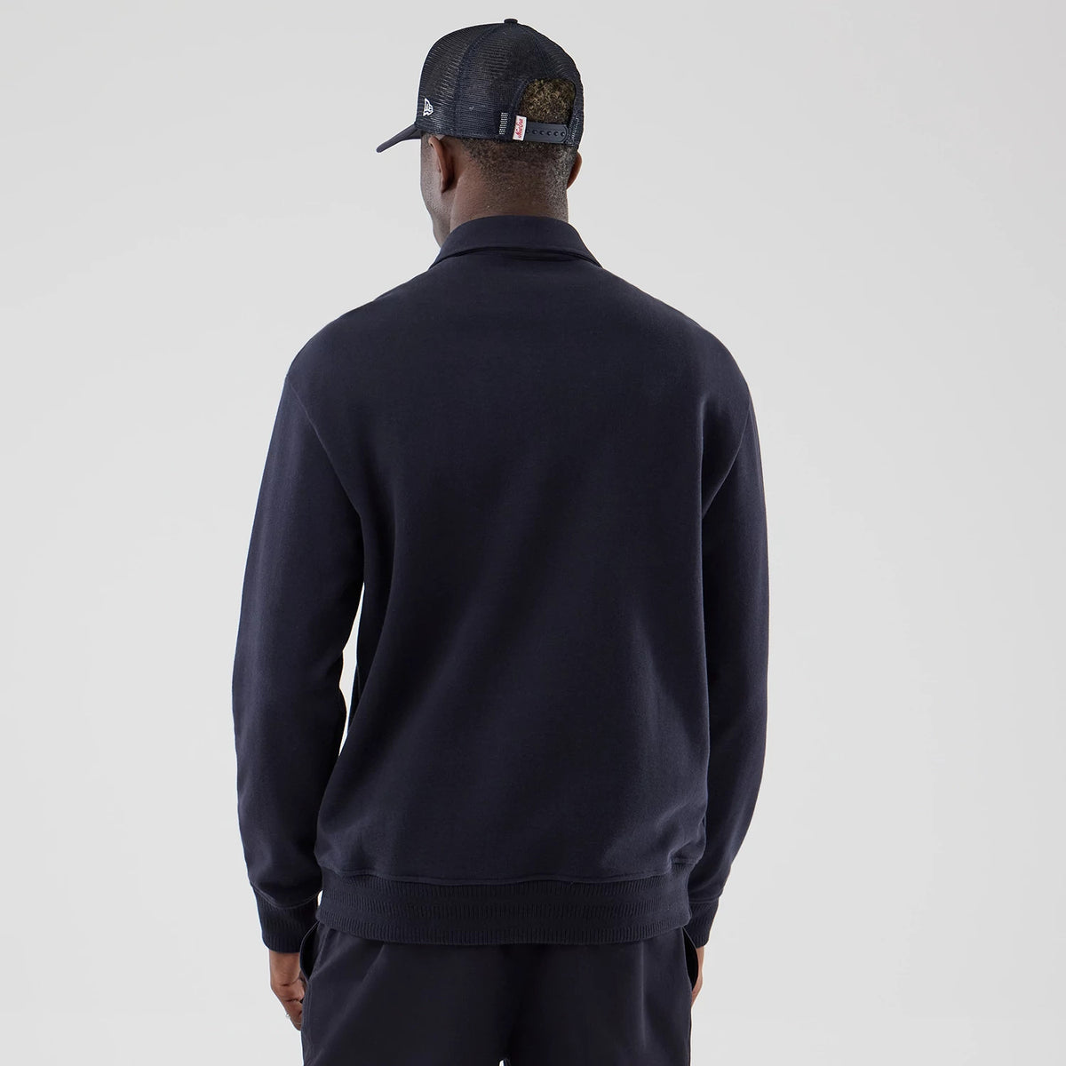 New Era LA Dodgers MLB Navy Oversized 1/4 Zip Sweater, back view on a model wearing a mesh cap, showcasing the plain navy fabric, relaxed fit, and ribbed hem, with a high collar and long sleeves completing the casual styling.
