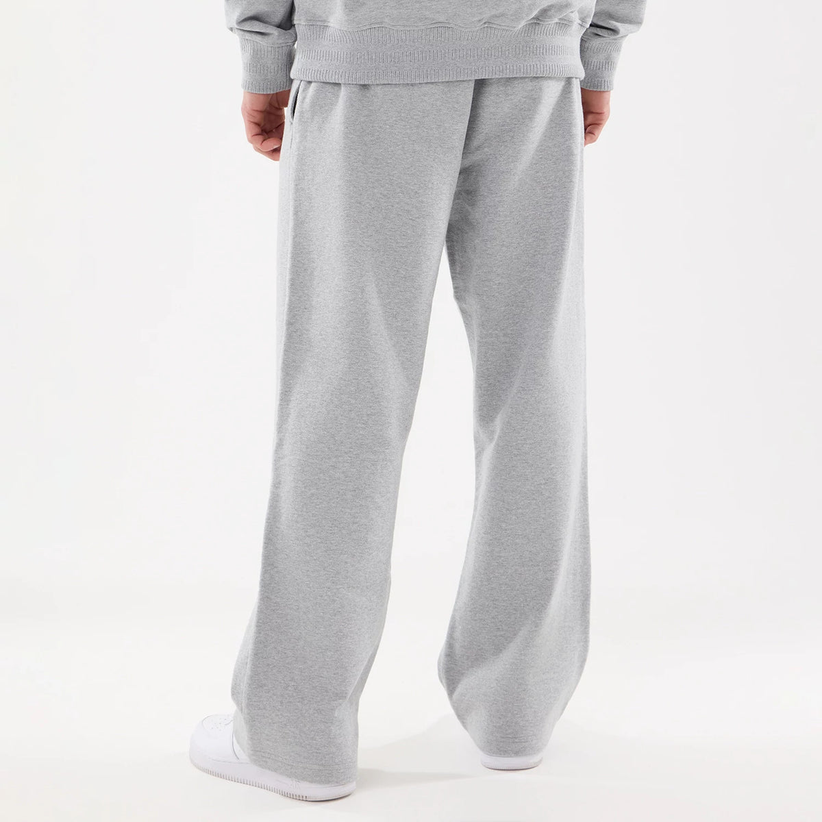 New Era New York Yankees MLB Straight Leg Grey Straight Leg Joggers, rear view on a model showing the loose fit and straight leg cut with stitching detail at the waistband, paired with white trainers for a casual sporty look.