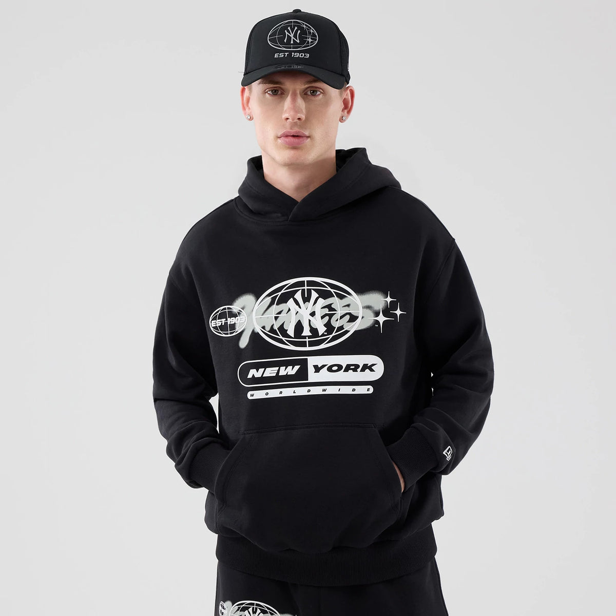 The model is wearing this MLB Logo Graphic New York Yankees Oversized Pullover Hoodie in black. 1