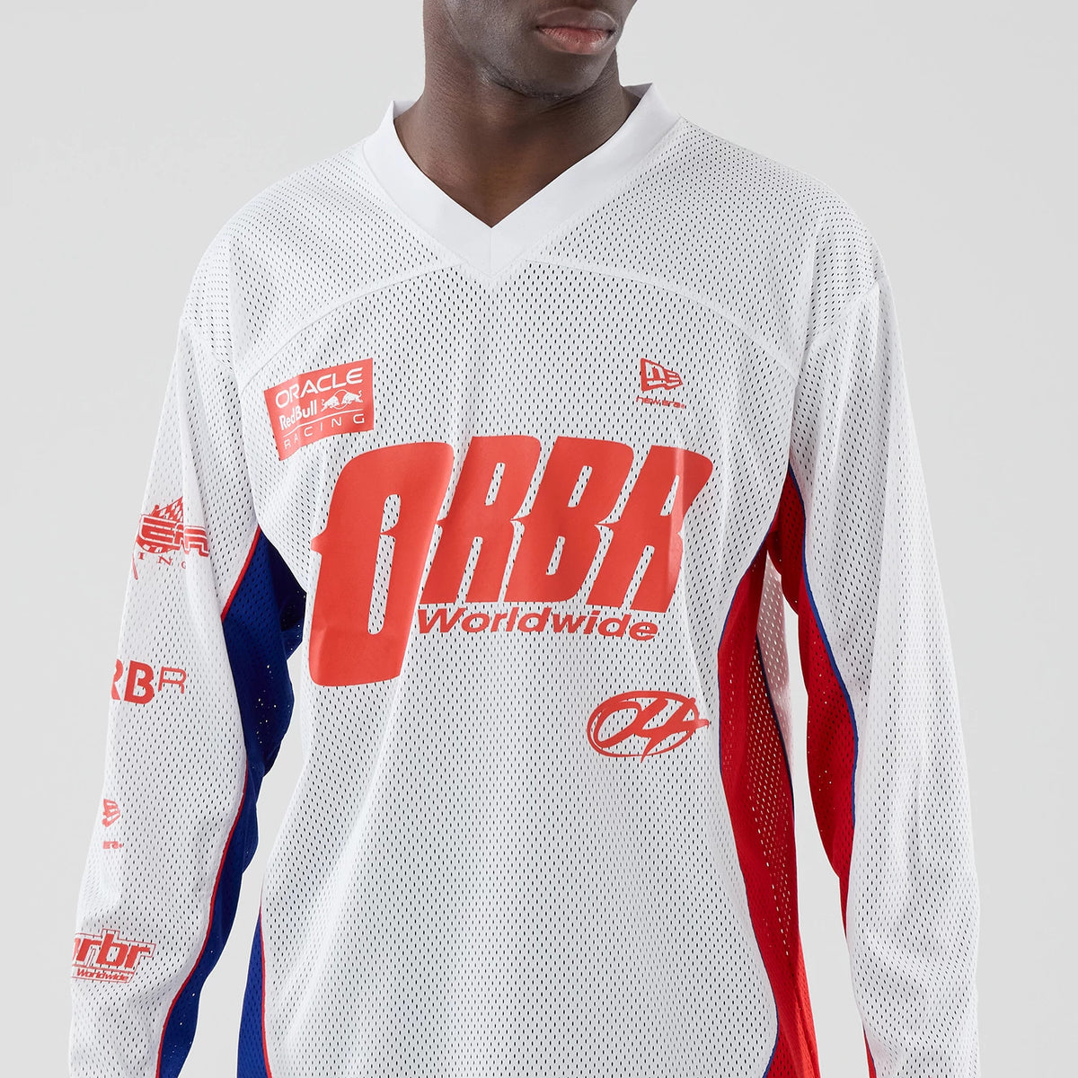 New Era Red Bull Racing White Hockey Jersey, front view on a model showing the red ORBR Worldwide lettering across the chest, with red and blue stripes down the sleeves and the New Era flag logo on the upper right chest.