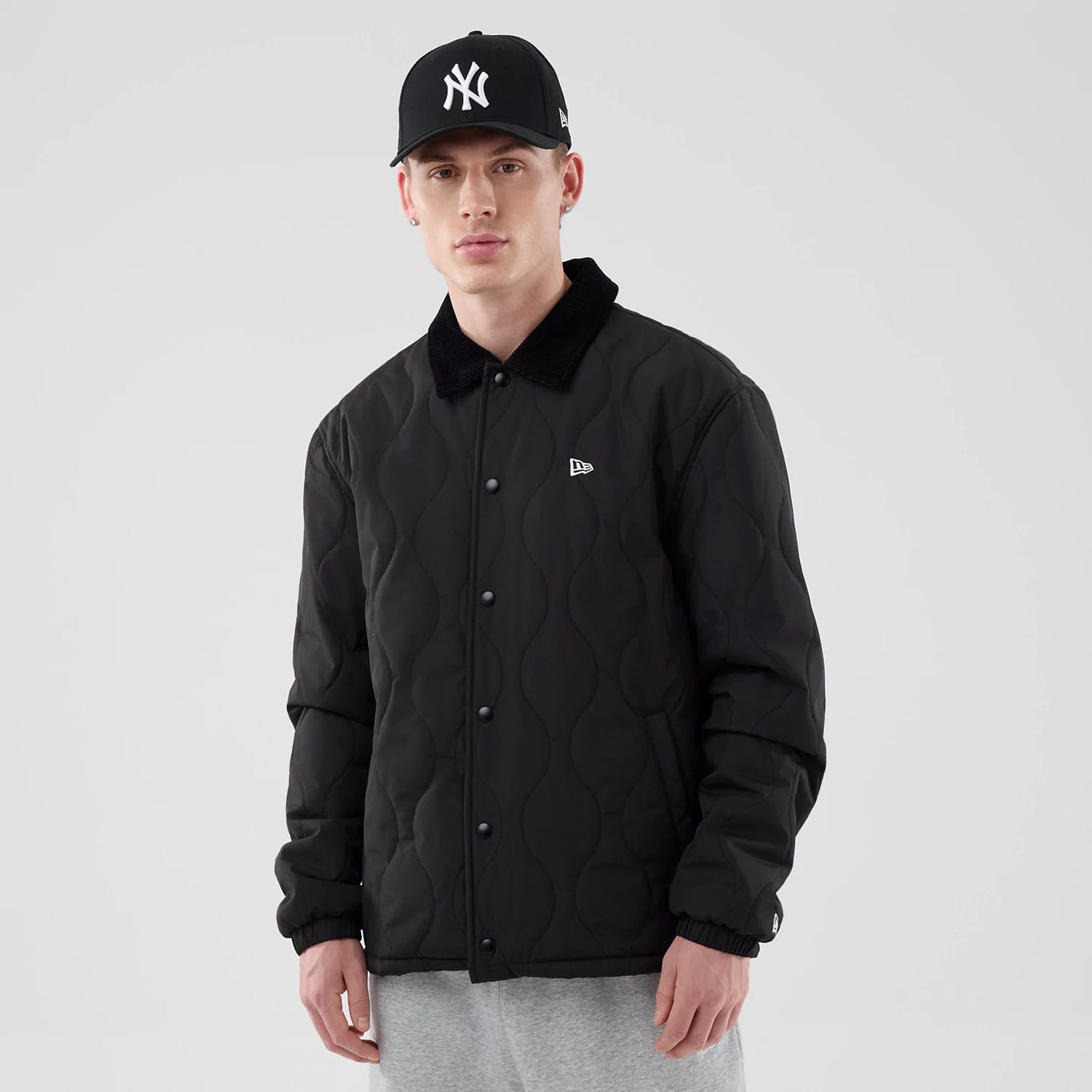 The model is wearing this New Era Quilted Coaches Jacket in black. 1