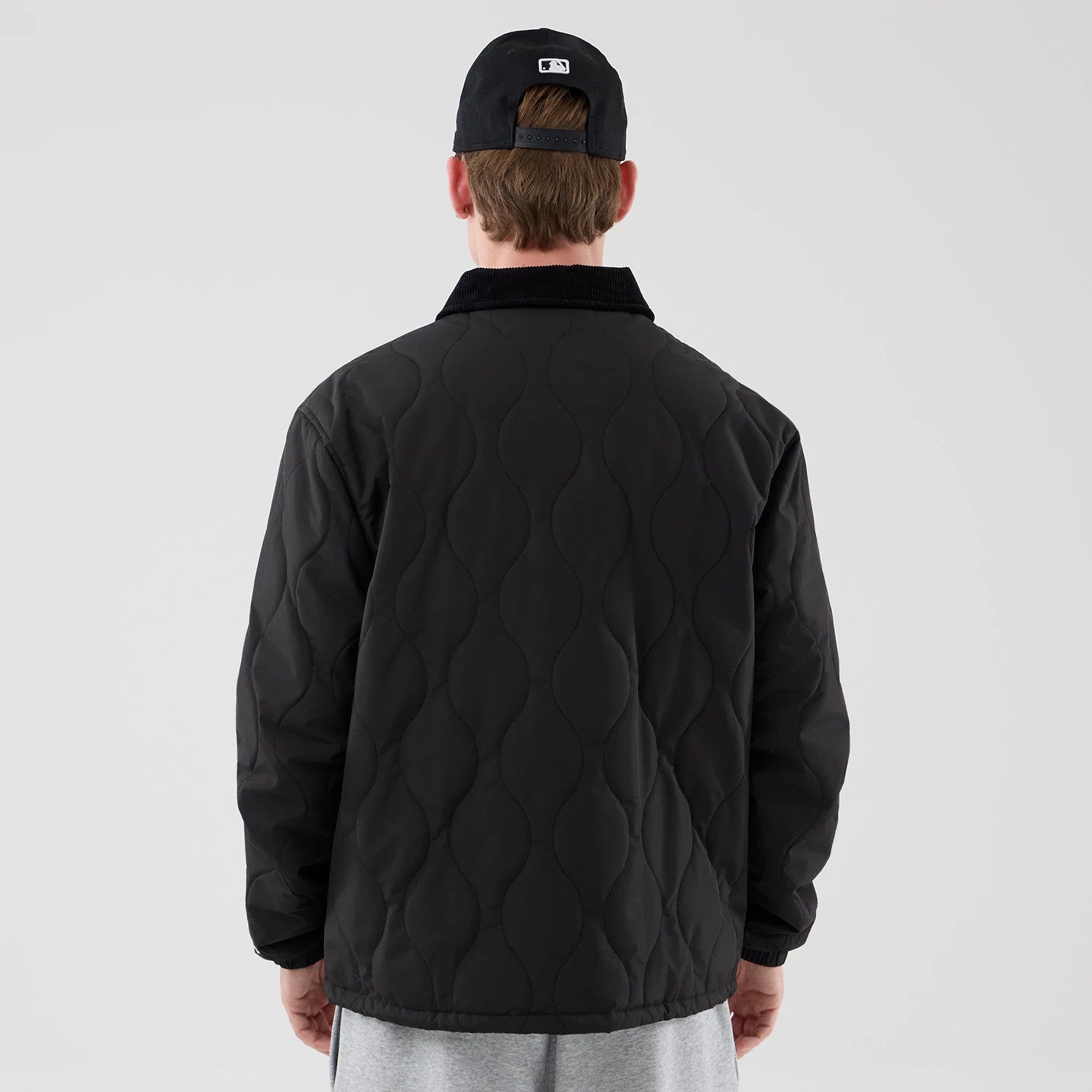 The model is wearing this New Era Quilted Coaches Jacket in black. 2