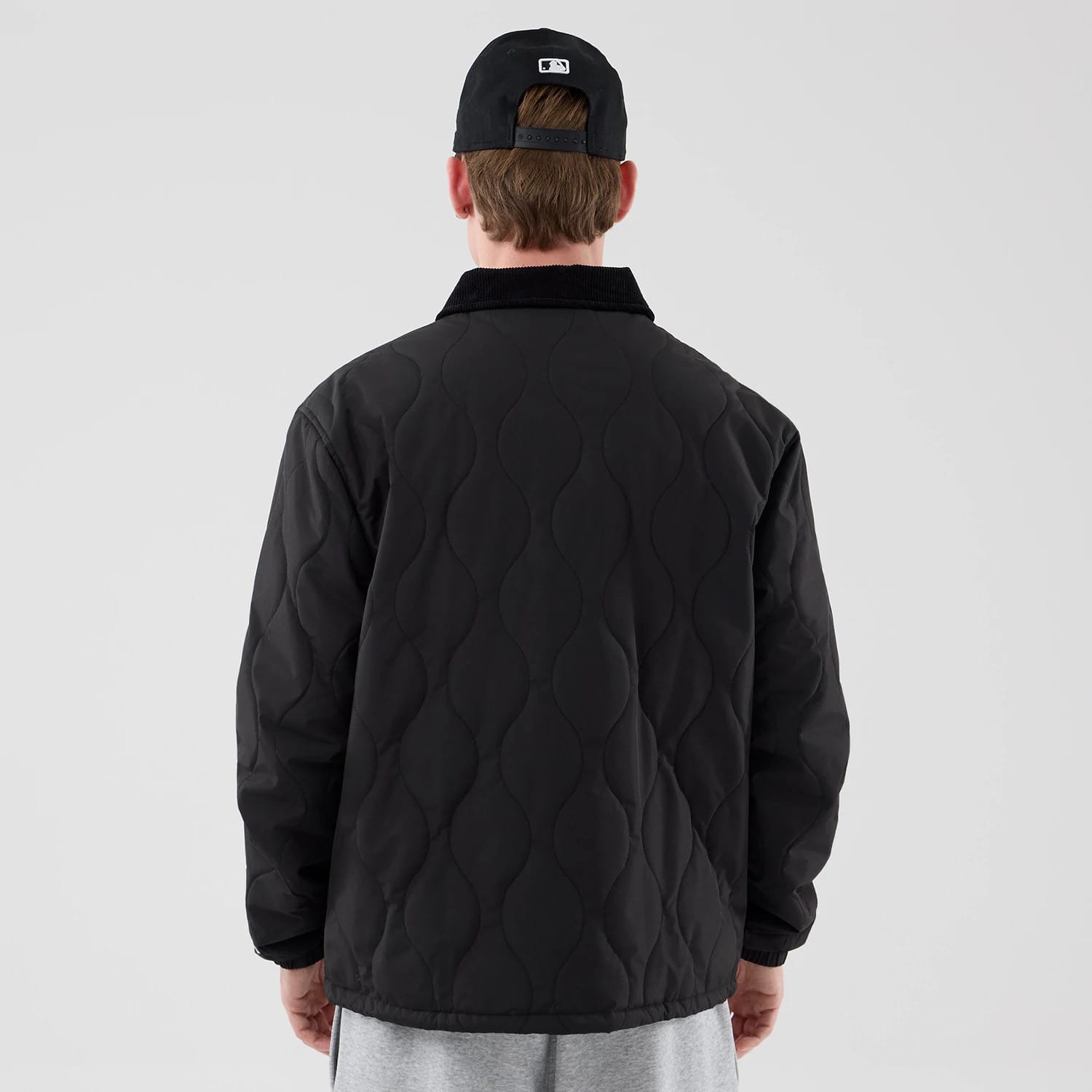 The model is wearing this New Era Quilted Coaches Jacket in black. 2