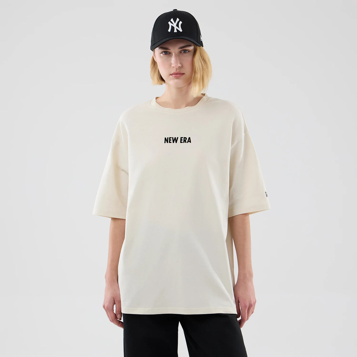 The model is wearing this New Era Cap Graphic Oversized T-Shirt in cream. 4