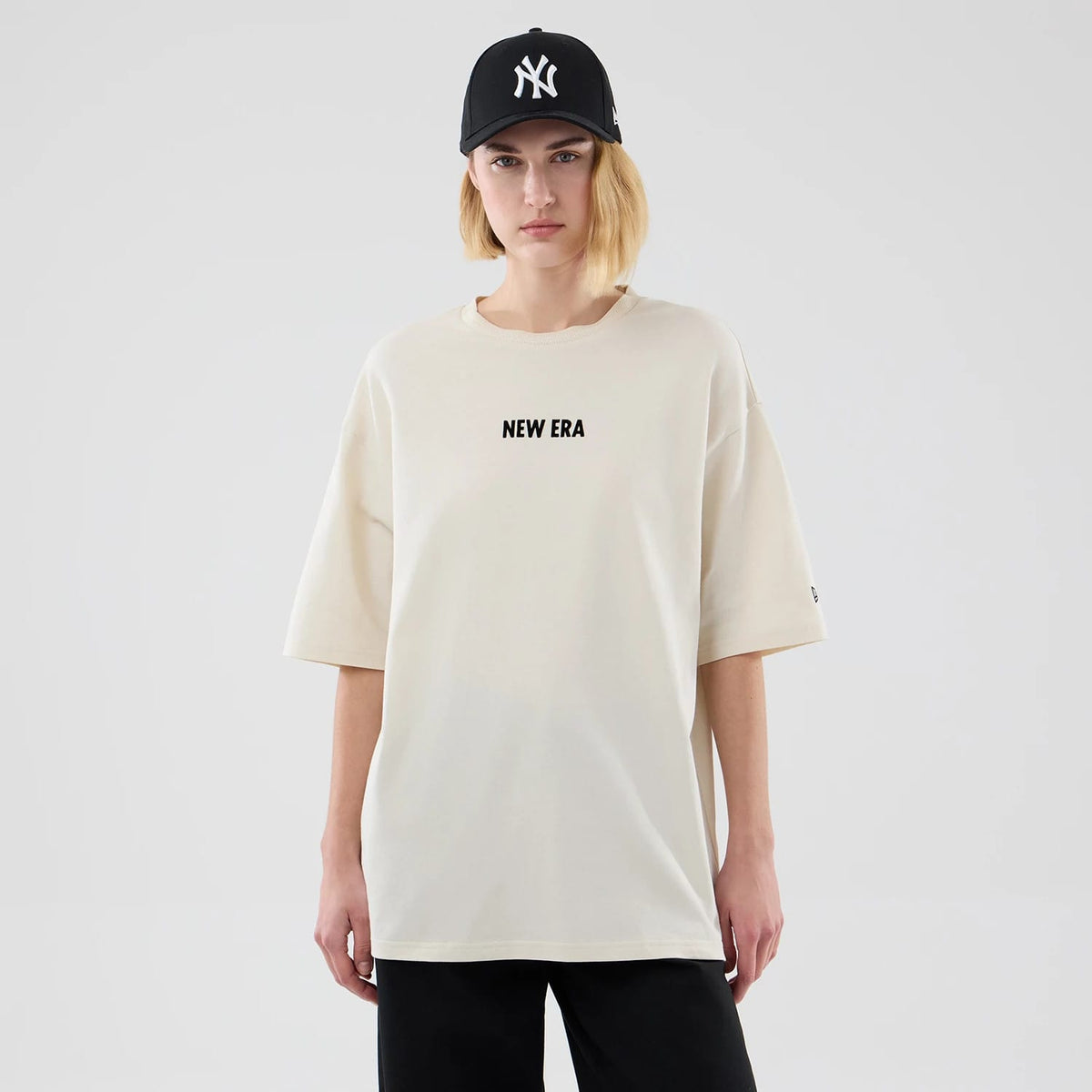 The model is wearing this New Era Cap Graphic Oversized T-Shirt in cream. 4