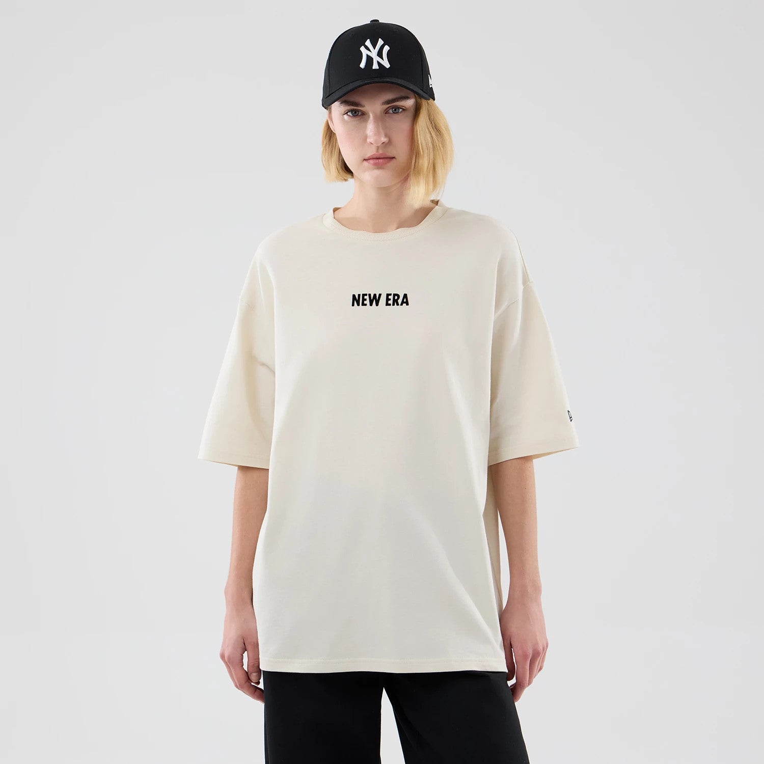 The model is wearing this New Era Cap Graphic Oversized T-Shirt in cream. 4