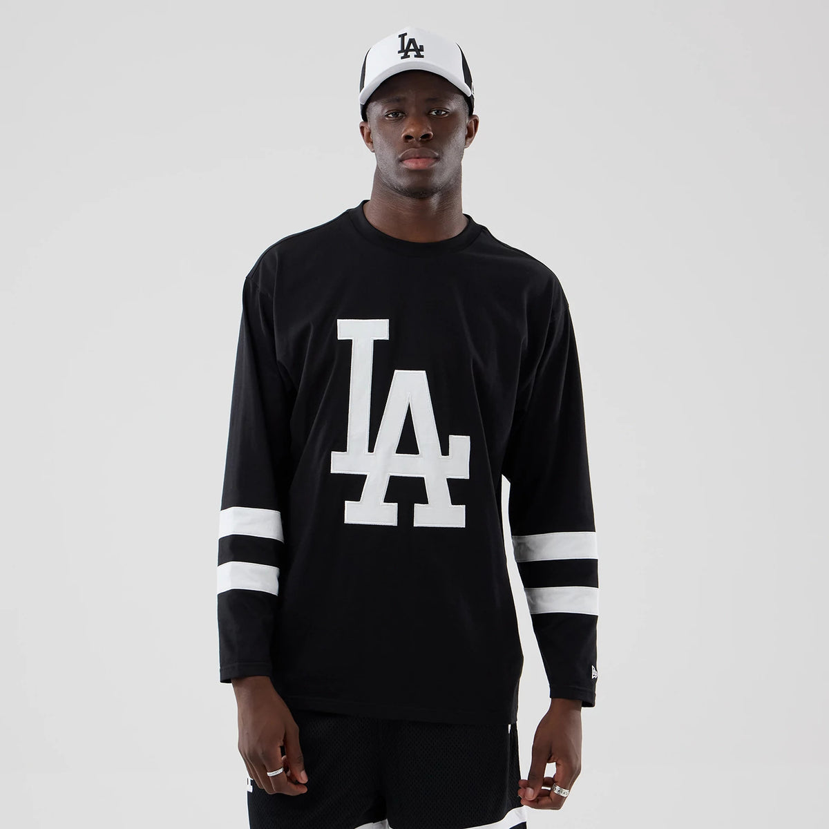 New Era LA Dodgers MLB Black Oversized Long Sleeve T-Shirt, front view on a model featuring a white embroidered LA logo centred on the chest, with horizontal white stripes around the sleeves and a small New Era flag logo on the left cuff.