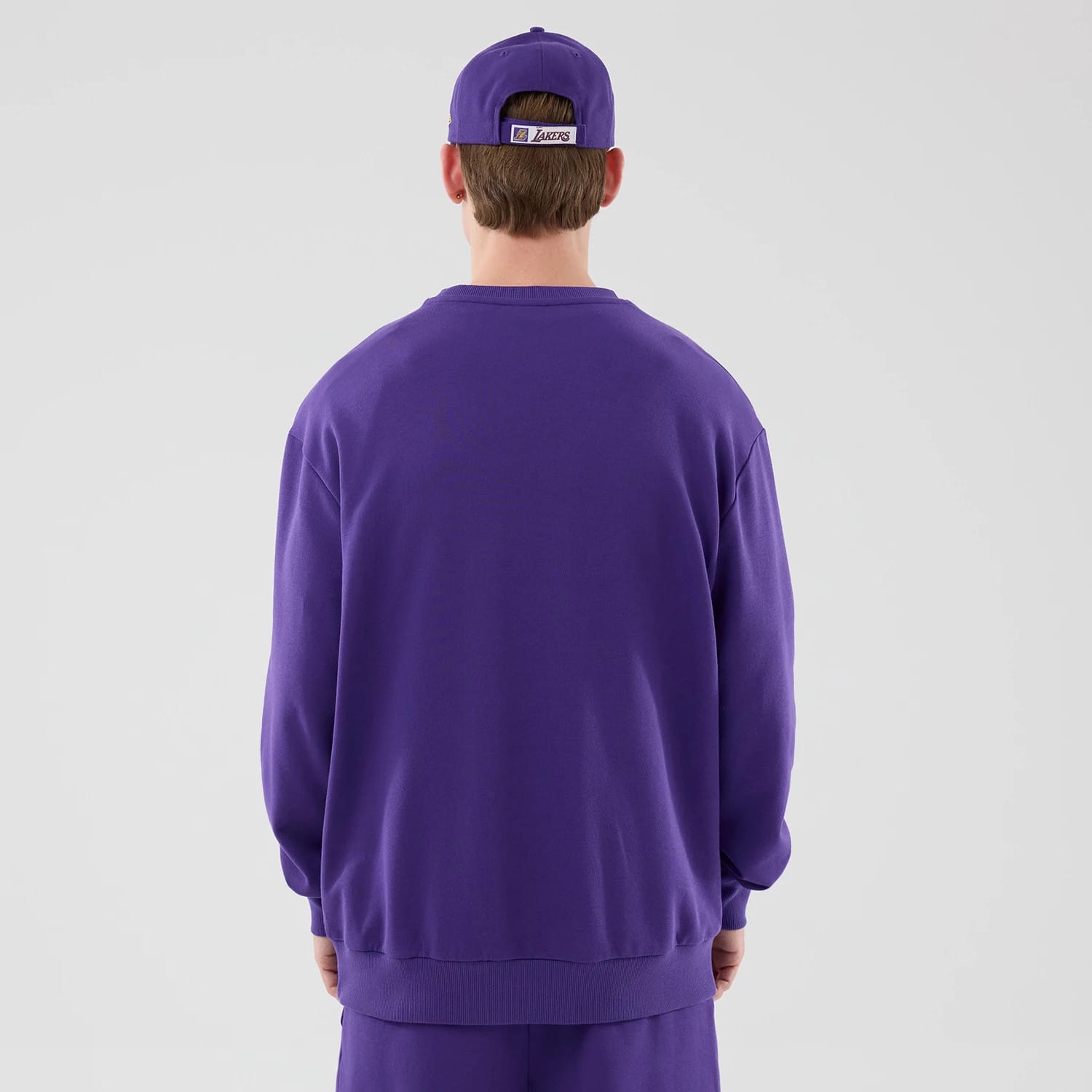 The model is wearing this NBA League Essential LA Lakers Oversized Crew Neck Sweater in purple. 2