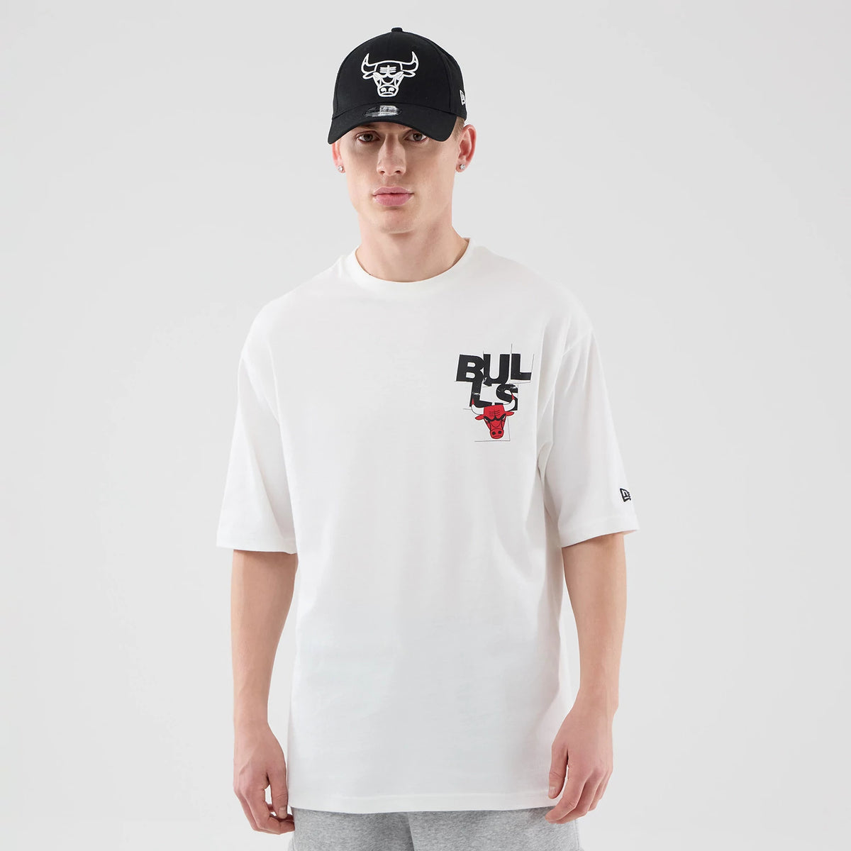 New Era Chicago Bulls NBA Player Graphic White Oversized T-Shirt, front view on a model with a black cap, featuring an eye-catching Bulls graphic and red bull emblem on the left chest, and an embroidered New Era logo on the left sleeve.