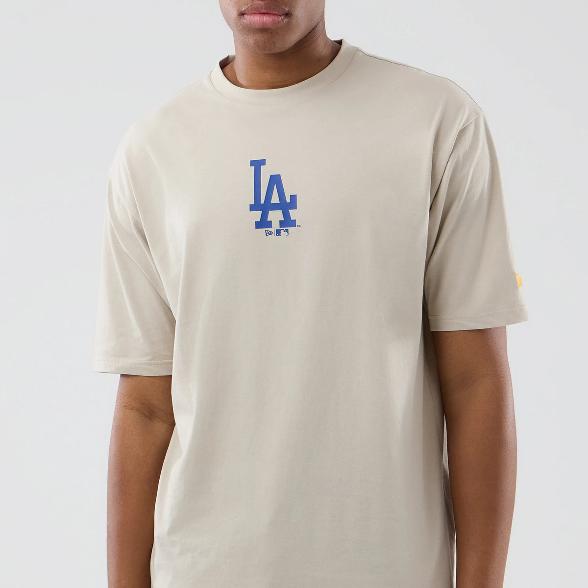 New Era LA Dodgers MLB Food Graphic Cream Oversized T-Shirt, front view on a model featuring a blue embroidered LA logo on the chest, relaxed short sleeves, and a small yellow embroidered New Era logo on the left sleeve.