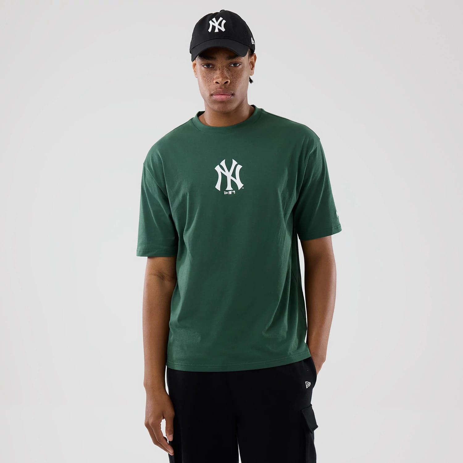 The model is wearing this MLB Food Graphic New York Yankees Oversized T-Shirt in dark green. 1