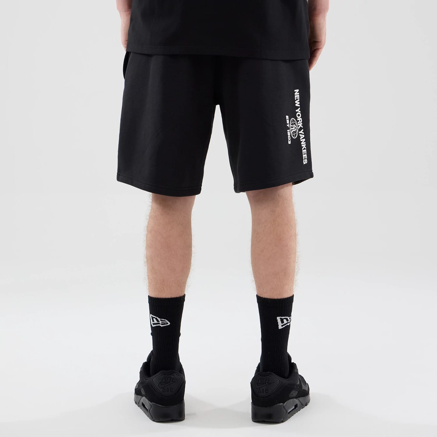 The model is wearing these MLB Logo Graphic New York Yankees Oversized Shorts in black. 2