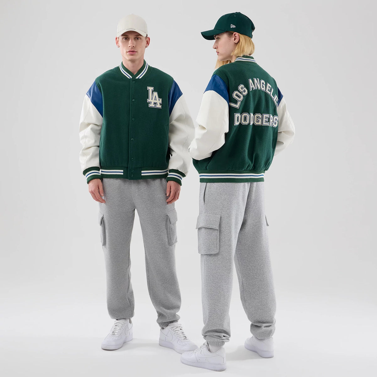 New Era LA Dodgers MLB Varsity Dark Green Jacket, front and back view showing a large embroidered LA logo on the chest, contrasting white sleeves with blue shoulder accents, and Los Angeles Dodgers lettering across the upper back.