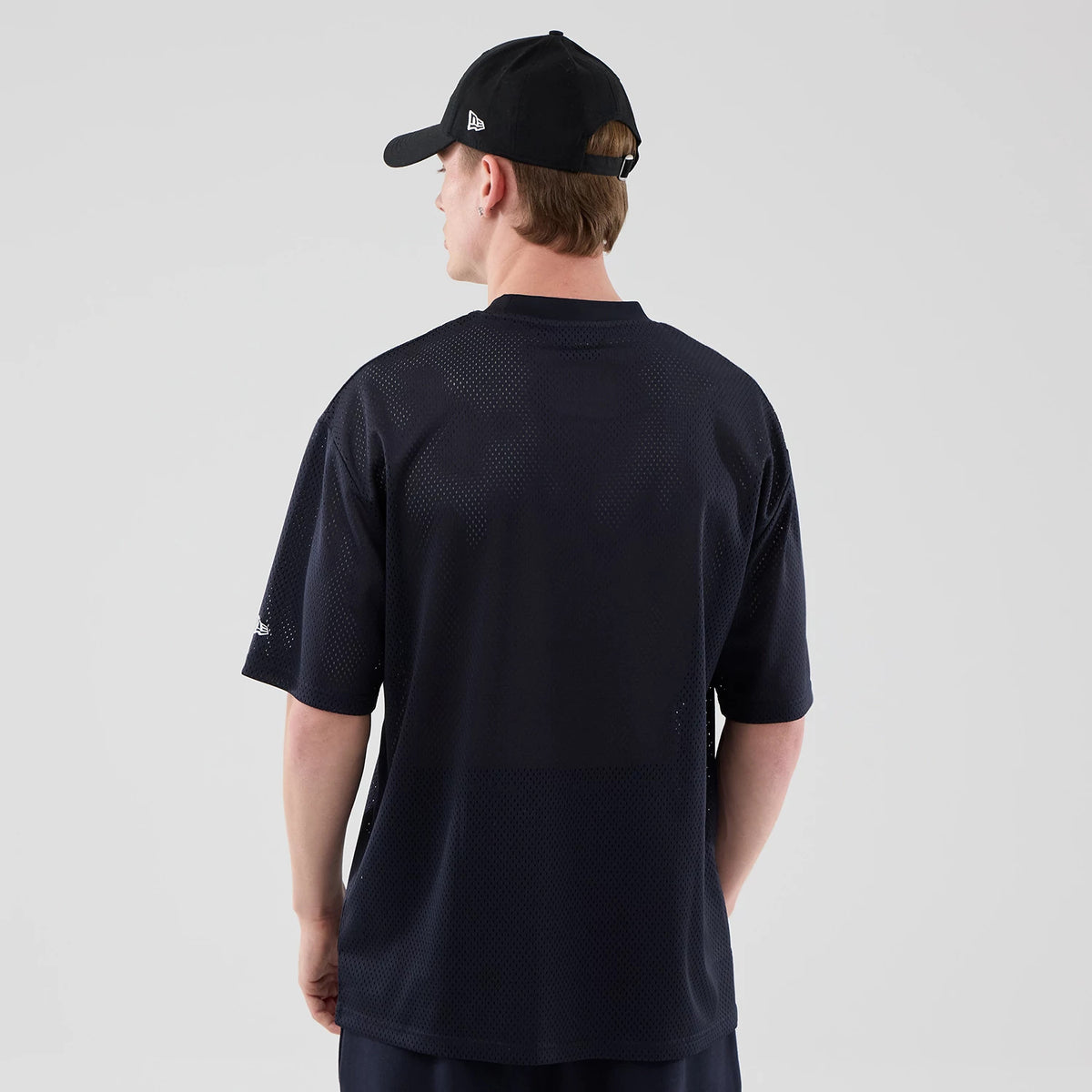 New Era LA Lakers NBA Core Plus Mesh Navy Oversized T-Shirt, back view on a model wearing a black cap, showing the navy mesh fabric with a relaxed fit, Lakers logo on the right sleeve, and round neckline.