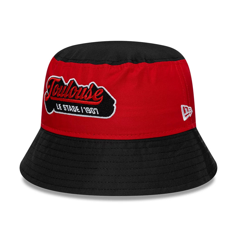New Era Youth Stade Toulousain Black Bucket Hat, front view showing the embroidered Toulouse script in red and white on the red band, the contrasting black top and visor, and the white New Era flag logo on the side.