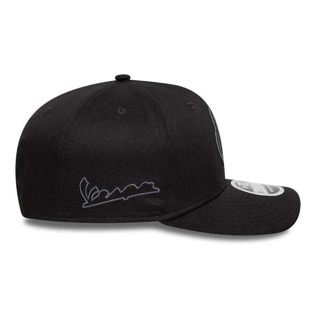 Vespa Black New Era 9SEVENTY Stretch Snap Adjustable Cap, side view showing the white embroidered Vespa script logo on the side panel, a curved black visor, and the 9SEVENTY size sticker on the top.