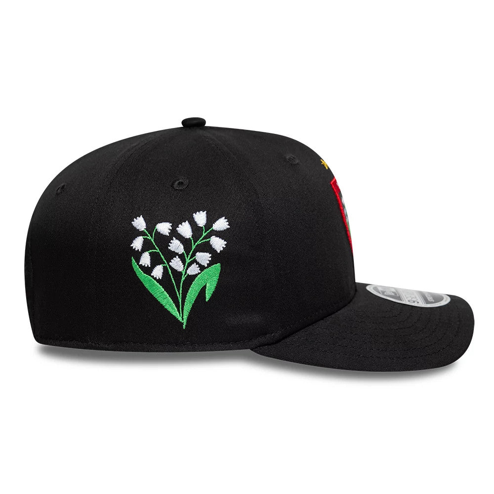 Rugby Club Toulon Lily Black New Era 9SEVENTY Stretch Snap Adjustable Cap, side view showing a white lily embroidered on the black crown, the curve of the black visor, and the texture of the fabric surrounding the 9SEVENTY size sticker.