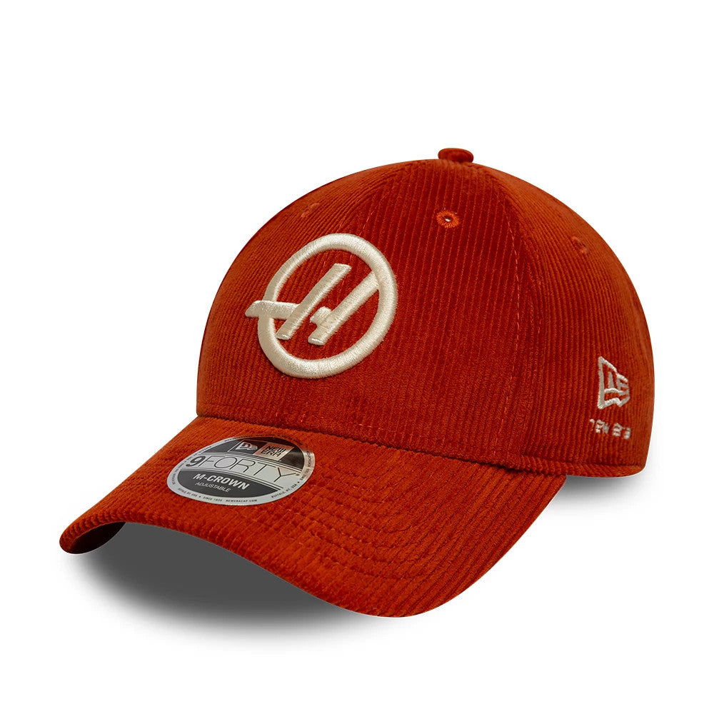 TGR Haas F1 Team Cord Red New Era 9FORTY M-Crown Adjustable Cap, three-quarter view showing a raised white embroidered Haas logo on the front panel, with a 9FORTY size sticker on the curved visor and New Era flag logo on the left side.