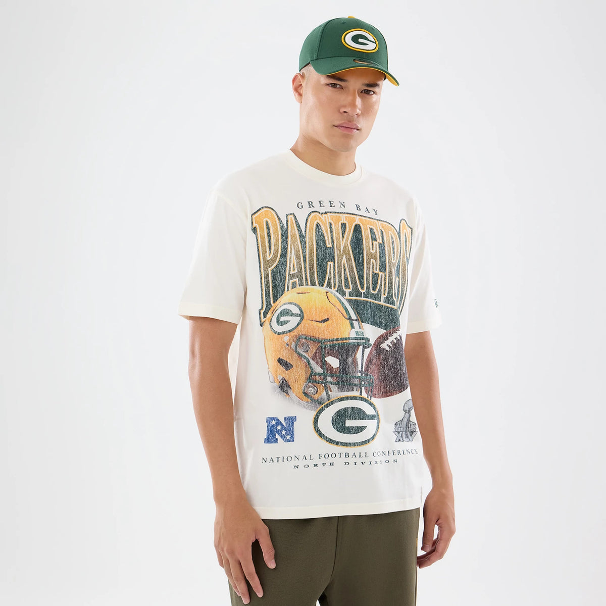 New Era Green Bay Packers NFL Sport Classic Cream T-Shirt, front view on-model showing a large Packers helmet graphic printed across the chest, stylised text reading Green Bay Packers above, and an embroidered logo on the left sleeve.