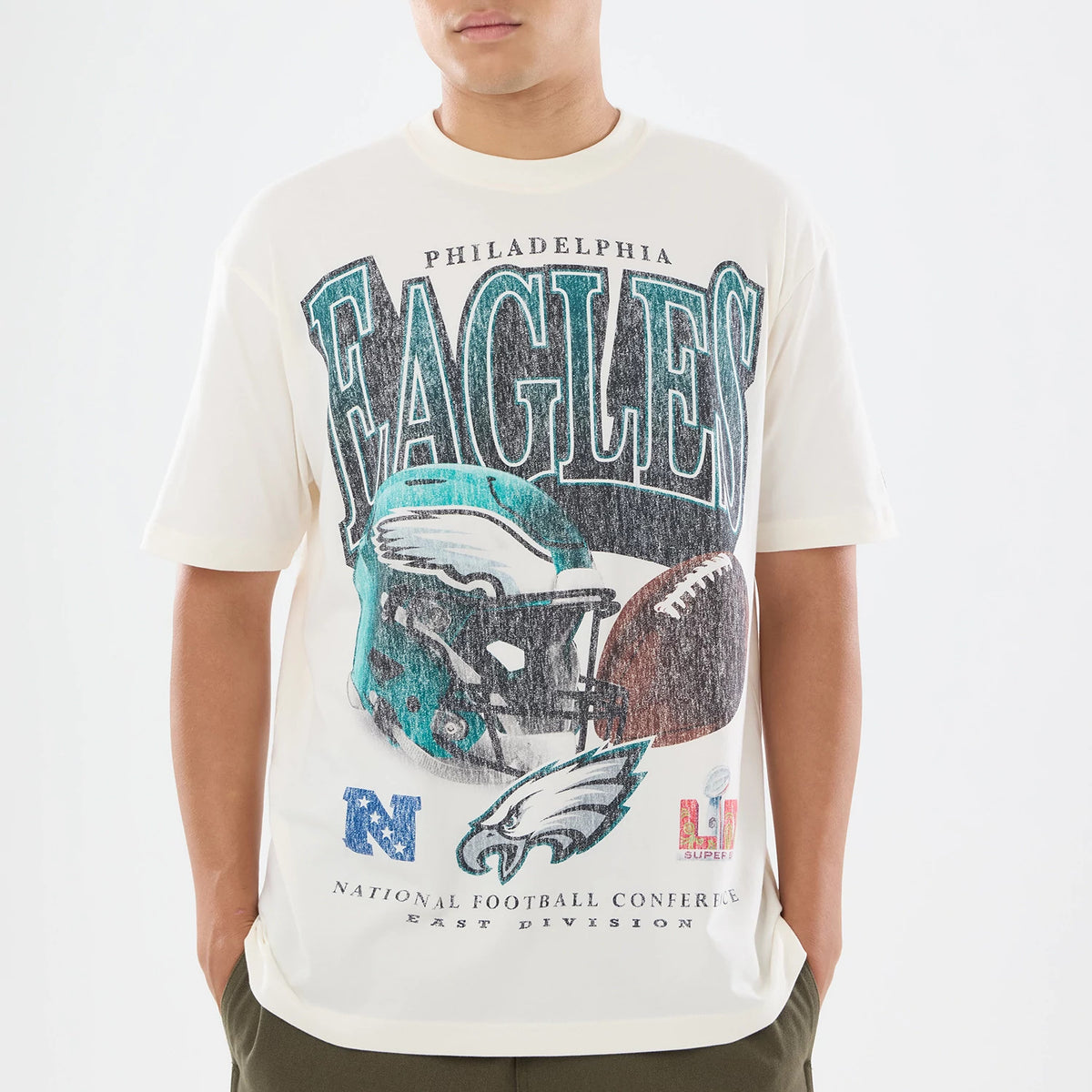 New Era Philadelphia Eagles NFL Sport Classic Cream T-Shirt, front view showing the distressed Eagles lettering across the chest above a large graphic of a football helmet and ball, with conference details below.
