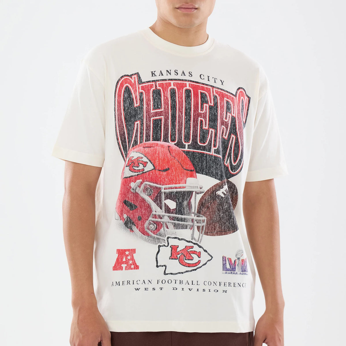 New Era Kansas City Chiefs NFL Sport Classic Cream T-Shirt, front view on a model featuring CHIEFS lettering across the chest, a large red helmet graphic below, smaller logos including the AFC and team logo printed at the bottom.