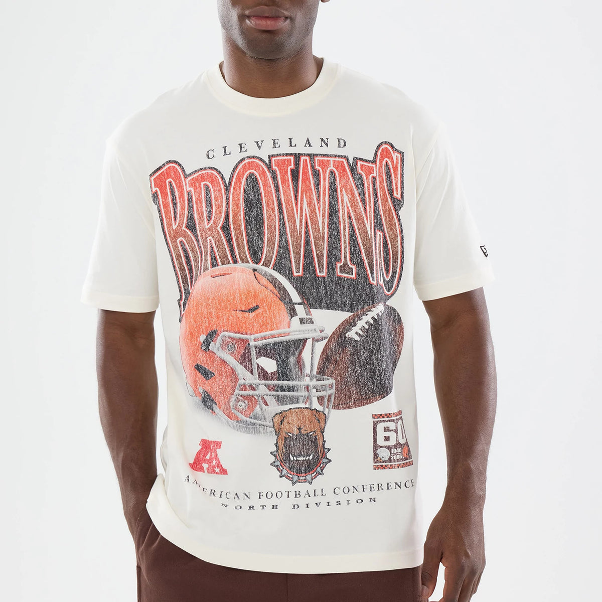 New Era Cleveland Browns NFL Sport Classic Cream T-Shirt, front view on a model showing large distressed Browns lettering with a detailed graphic of a football helmet and ball, an embroidered New Era logo on the left sleeve.