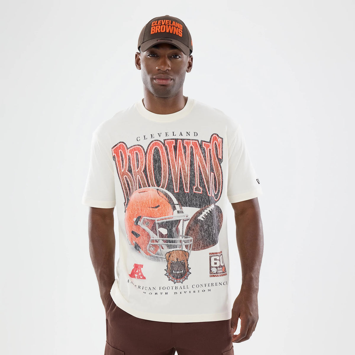 New Era Cleveland Browns NFL Sport Classic Cream T-Shirt, front view on-model showing the large lettering Browns above an illustrated football helmet, a printed New Era logo on the left sleeve, and the model wearing a matching Cleveland Browns cap.