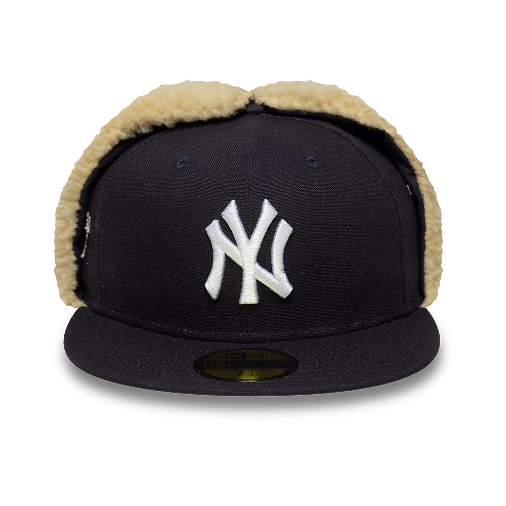 New York Yankees MLB World Series Navy Dogear New Era 59FIFTY Fitted Cap, front view showing the white raised embroidered NY logo on the structured navy crown, with tan faux fur-lined ear flaps and a gold 59FIFTY size sticker on the visor.