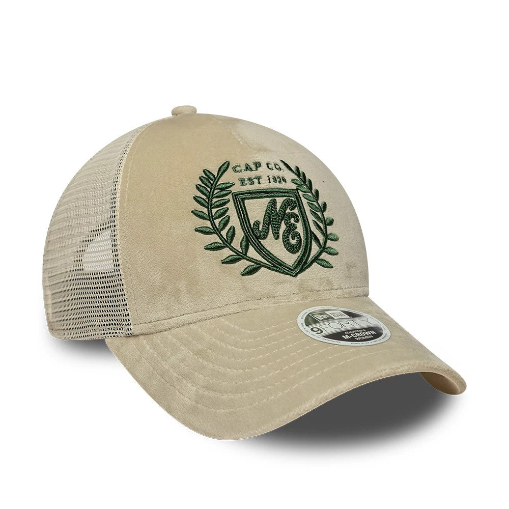 Womens New Era Velour Cream 9FORTY M-Crown A-Frame Trucker Adjustable Cap, three-quarter view showing a green embroidered crest logo on the front panel, a cream mesh back, and a curved cream visor with a 9FORTY size sticker on top.