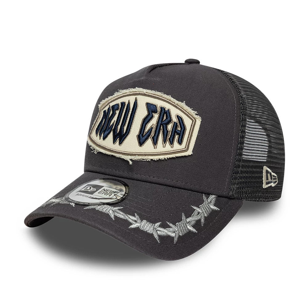 New Era Distressed Patch Charcoal 9FORTY E-Frame Trucker Adjustable Cap, three-quarter view showing a frayed black and beige patch with New Era lettering on the front panel, a barbed wire pattern on the curved charcoal visor.