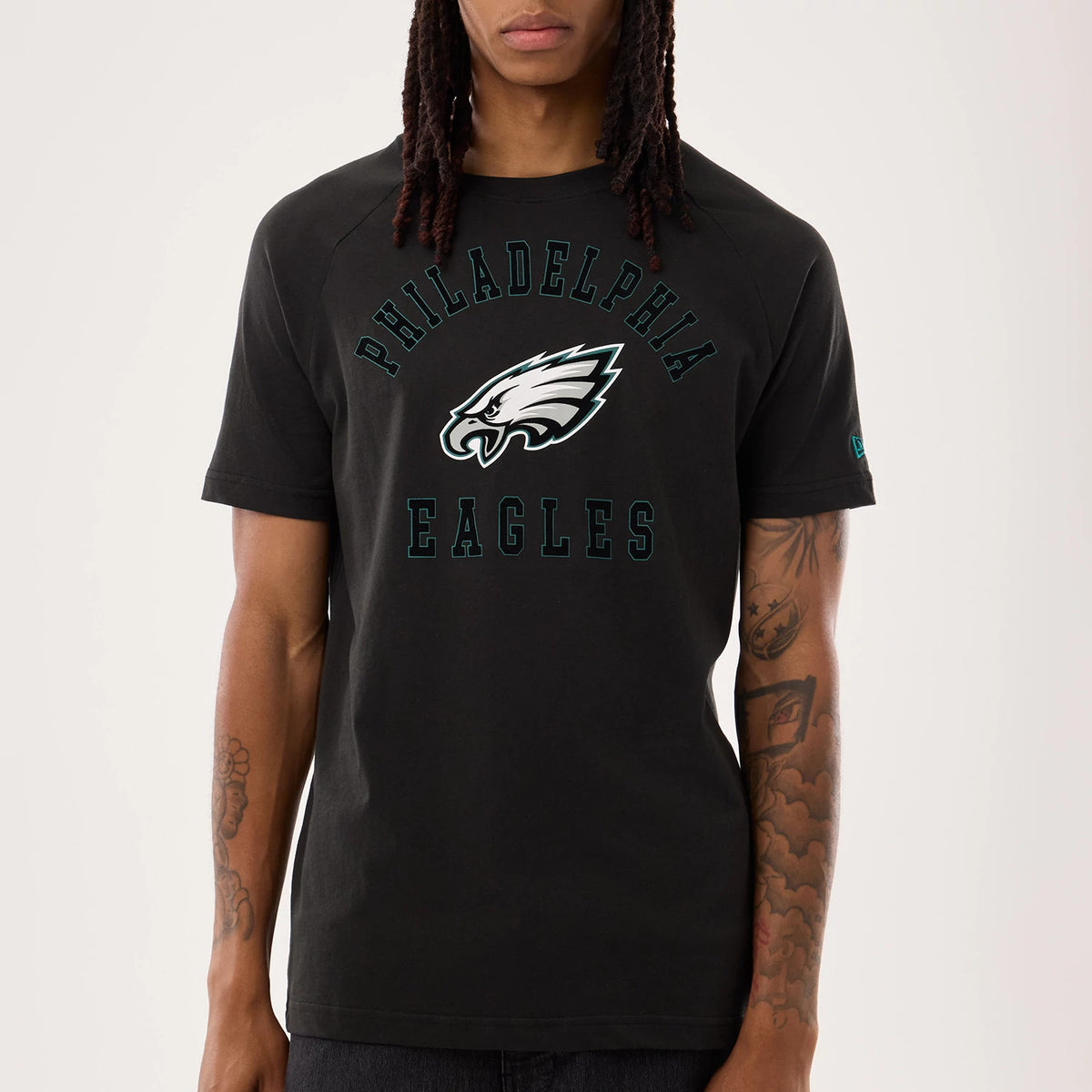New Era Philadelphia Eagles NFL Sideline 2026 Black T-Shirt, front view showing the Philadelphia Eagles text arching above and below a large, printed eagle logo, with a small embroidered New Era logo on the left sleeve worn by a model.