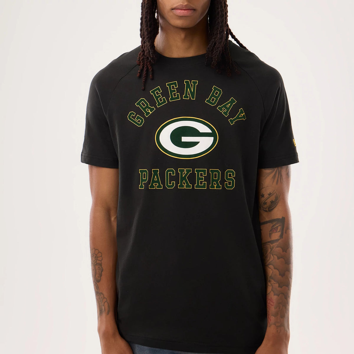 New Era Green Bay Packers NFL Sideline 2026 Black T-Shirt, front view showing Green Bay Packers lettering in green with gold outline arching over and under a large embroidered team logo centred on the chest, model styled with natural hair.