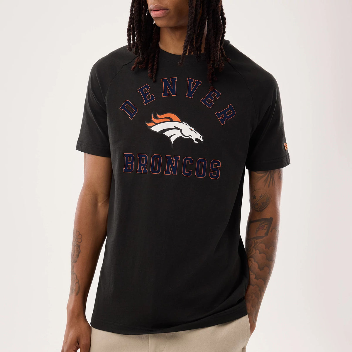 New Era Denver Broncos NFL Sideline 2026 Black T-Shirt, front view on a model displaying the large printed Denver Broncos logo on the chest, featuring orange and white lettering over the black fabric.