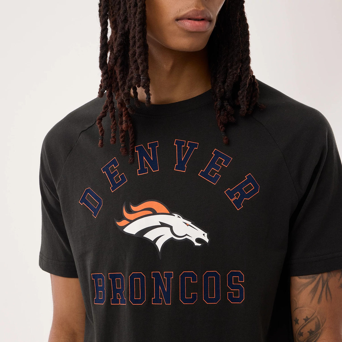 New Era Denver Broncos NFL Sideline 2026 Black T-Shirt, front view on a model showing a printed Denver Broncos logo with a white horse and orange mane centred on the black fabric, surrounded by large orange outline Denver and Broncos lettering.