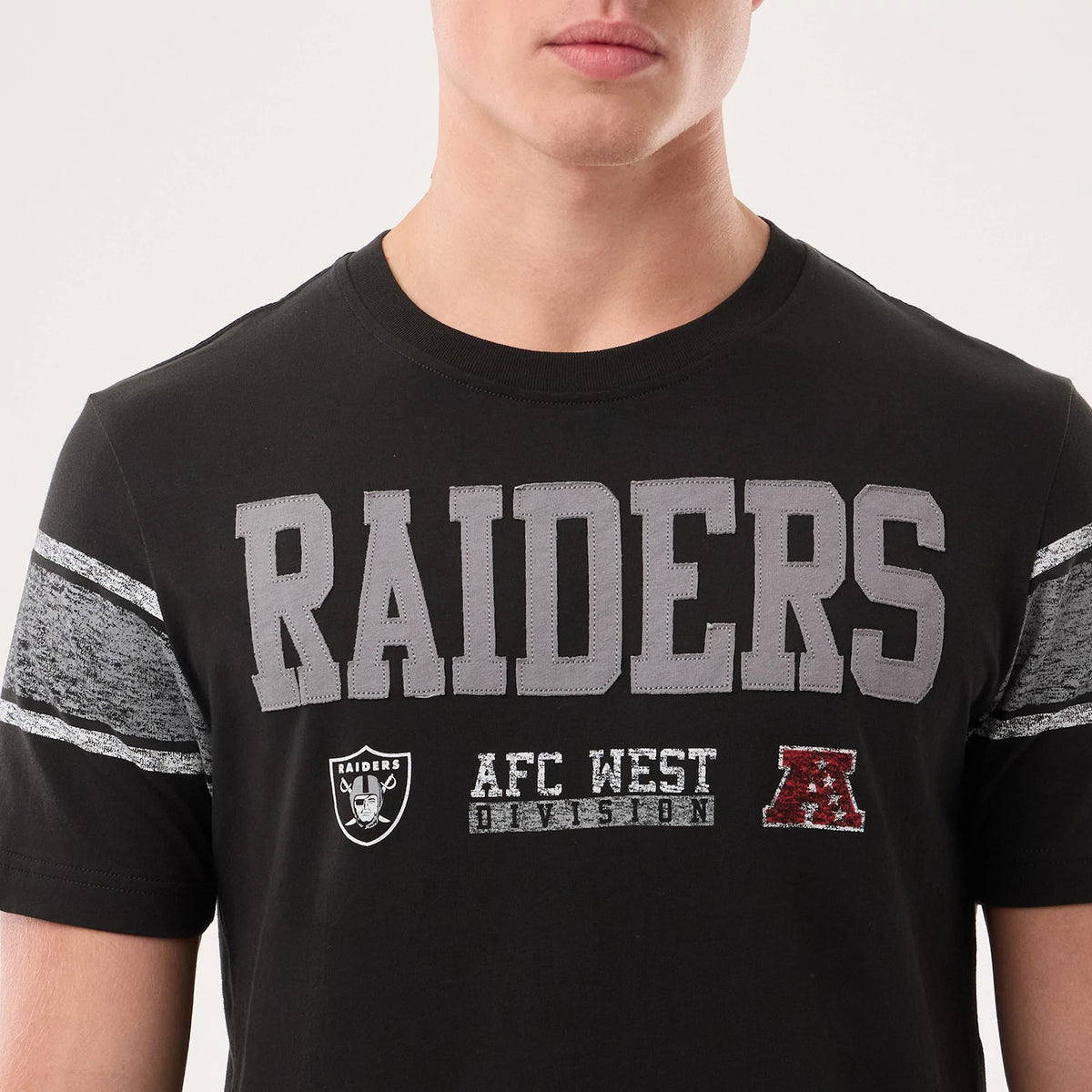 New Era Las Vegas Raiders NFL Sideline 2026 Black T-Shirt, front view showing large grey raised RAIDERS lettering across the chest, a printed Raiders logo and AFC West Division text below, with textured grey stripes on the sleeves.