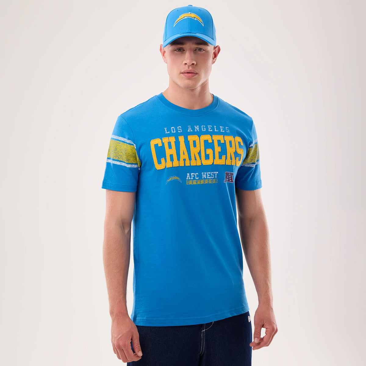 New Era LA Chargers NFL Sideline 2026 Blue T-Shirt, front view on-model showing yellow CHARGERS lettering across the chest, smaller Los Angeles above, striped yellow accents on the sleeves, and a printed team logo and AFC West lettering below.