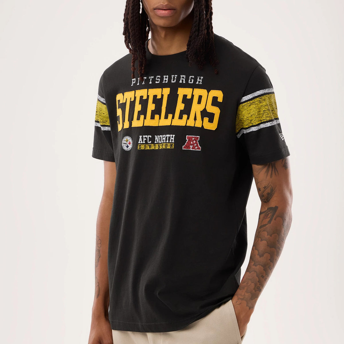 New Era Pittsburgh Steelers NFL Sideline 2026 Black T-Shirt, front view on a model showing yellow Steelers lettering across the chest with Pittsburgh above, a New Era embroidered logo on the sleeve, and textured stripe details on the sleeves.