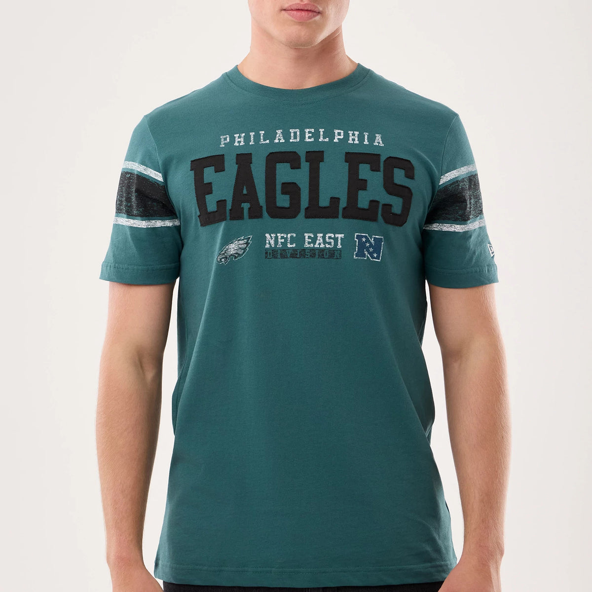 New Era Philadelphia Eagles NFL Sideline 2026 Dark Green T-Shirt, front view on-model showing the black embroidered Eagles lettering centred across the chest, flanked by printed team logos and NFC East text.