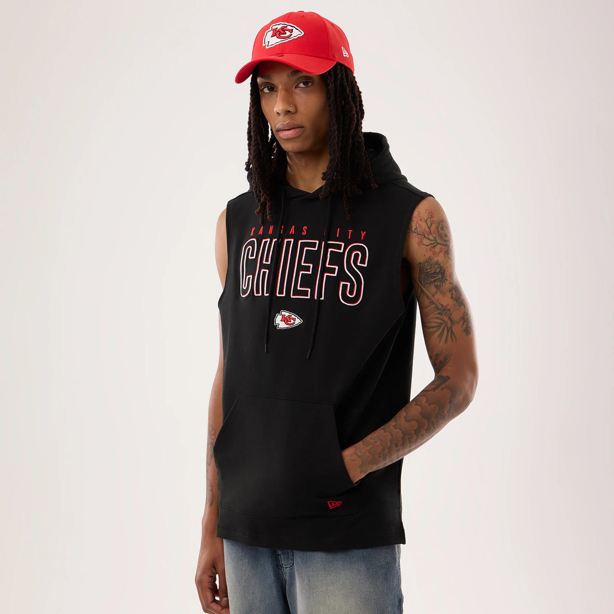 New Era Kansas City Chiefs NFL Sideline 2026 Black Tank Top, front view on a model wearing a red cap, featuring the Kansas City Chiefs lettering across the chest, an embroidered team logo underneath, and a drawstring hood above a kangaroo pocket.