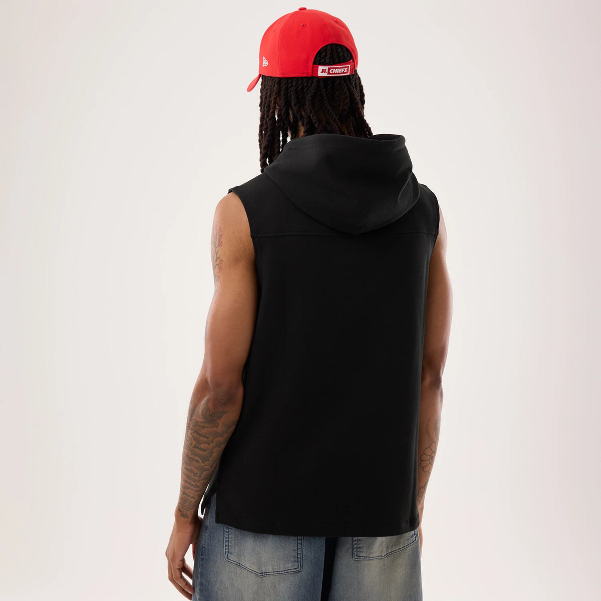New Era Kansas City Chiefs NFL Sideline 2026 Black Tank Top, back view on a model showing the sleeveless black design with a relaxed fit, hoodie-style collar, and athletic cut paired with a red cap.